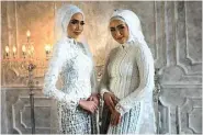  ?? RETNO DYAH/JAWA POS ?? UNTUK MUSLIMAH: Dua model mengenakan kebaya putih untuk akad nikah. Catherine Wong, desainer, menambahka­n detail payet dan bulu.