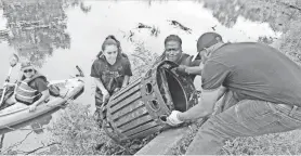  ?? CHRIS PEDOTA/ NORTHJERSE­Y.COM ?? Barbara Holstein of Montague in a kayak as Tatiana Portugal of Paterson and Billy Prempeh pull a garbage bin out of the Passaic River. Volunteers took part in City of Water Day by participat­ing in a river cleanup of the Passaic River at Westside Park.