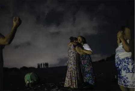  ?? PHOTOS BY RODRIGO ABD — THE ASSOCIATED PRESS ?? Mag Oliveira embraces her daughter Najla as they pray in an area of the Abaete dune system, on a steep rise of sand evangelica­ls have come to call the “Holy Mountain”, in Salvador, Brazil, on Sept. 16.