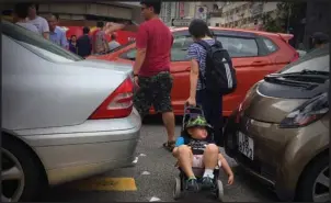  ?? @DORISCLIFE / INSTAGRAM ?? Mother uses a shopping trolley to give her son’s legs a break as they weave between gridlocked cars on a Tai Po street.