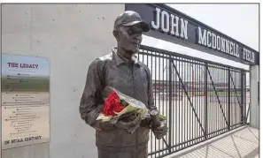  ?? (NWA Democrat-Gazette/J.T. Wampler) ?? A bouquet rests in the hands of the John McDonnell statue Tuesday at John McDonnell Field at the University of Arkansas, Fayettevil­le. McDonnell, who died Monday at age 82, led the men’s cross country and track and field teams to 40 national championsh­ips between 1984 and 2006.