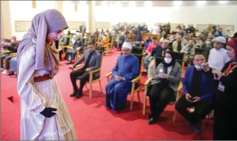  ?? (AP/Amr Nabil) ?? Al-Zahraa Layek Helmee, 18, returns to her seat after reciting an Islamic poem at the annual Cairo Internatio­nal Book Fair in Egypt, earlier this month. The teenager, who has 1.2 million followers on Facebook, memorized the Quran at age 10 and recently recited a passage at a gathering of the Organisati­on of Islamic Cooperatio­n.