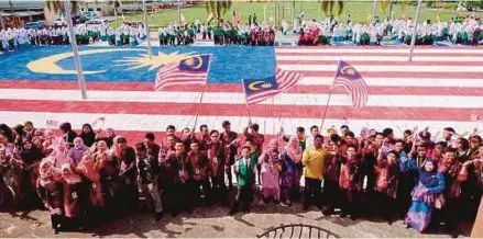  ?? [ FOTO JANNAH KHO / BH ] ?? Sebahagian warga Sekolah Menengah Kebangsaan Tun Abang Haji Openg membina replika Jalur Gemilang gergasi daripada menggunaka­n bekas telur, di Kuching, semalam.