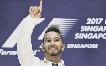  ??  ?? 0 Britain’s Lewis Hamilton celebrates on the podium after his victory in the Singapore Grand Prix.