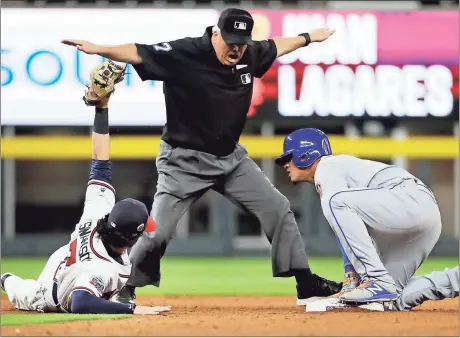  ?? David Goldman / The Associated Press ?? Atlanta’s Dansby Swanson (left) holds up the ball as New York Mets’ Juan Lagares is called safe at second base by umpire Larry Vanover on a double.