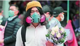  ??  ?? Un joven de Hong Kong con un ramo de flores y una máscara especial