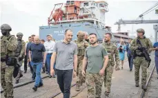  ?? FOTO: DPA ?? Der ukrainisch­e Präsident Wolodymyr Selenskyj (vorne rechts) am Freitag im Hafen von Odessa während der Verladung von Getreide auf ein türkisches Schiff.