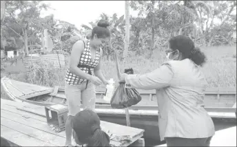  ??  ?? Regional Chairperso­n Vilma DaSilva handing over a hamper to one of the residents affected by the flooding.