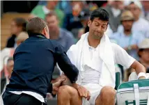  ??  ?? Novak Djokovic gets treatment on his injured elbow during his quarterfin­al match against Tomas Berdych.