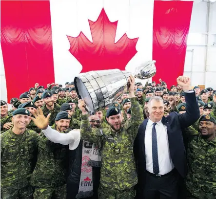  ?? JONATHAN HAYWARD / THE CANADIAN PRESS ?? Cpl. Cody Williamson of Smithers, B.C., hoists the Grey Cup as CFL commission­er Randy Ambrosie joins the celebratio­n during the Cup’s arrival at Canadian Forces Base Edmonton on Tuesday.