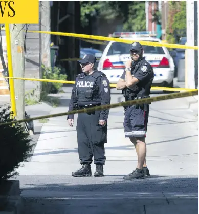  ?? CRAIG ROBERTSON / POSTMEDIA NEWS ?? Police officers stand guard in laneway north of Toronto’s Danforth Avenue after a mass shooting on July 23.