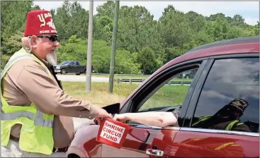  ?? Doug Walker / Rome News-Tribune ?? Shriner Bob Mount takes a donation from a motorist at the intersecti­on of Kingston Road and the bypass. The Shriners dedicate proceeds from the bucket drives to help pay expenses of children and their families at Shrine hospitals across the nation.