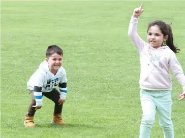  ??  ?? Future cricketers three year old Levi Wells and his five year old sister Jaida Wells enjoy playing on the field before the match.