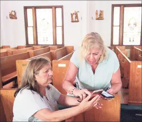  ??  ?? Antonia D’Amico, president of the Madonna Di Canneto Society, seated, and former parishione­r Phyllis T. Cecio go over photos and emails about the missing painting at Sacred Heart Church in Stamford on Wednesday.