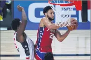  ?? ASHLEY LANDIS — THE ASSOCIATED PRESS ?? Philadelph­ia 76ers guard Ben Simmons (25) grabs a rebound in front of Washington Wizards center Thomas Bryant (13) during the second half of an NBA basketball game Wednesday, Aug. 5, 2020 in Lake Buena Vista, Fla.