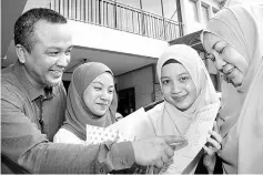  ??  ?? Najla (second right), her father Omar Alli (left), her mother (right) and her youngest sister looking at her STPM results. — Photos by Chimon Upon