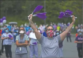  ?? (AP/Jessie Wardarski) ?? Jennifer Esken, staff accountant for Allied Services Skilled Nursing & Rehab Center, waves purple flags as she and Allied staff members celebrate Andres and Cappelloni.