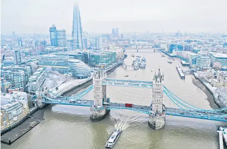  ?? — AFP file photo ?? An aerial view shows snow-covered offices and buildings including the Shard skyscraper, as a boat passes under Tower Bridge on the River Thames, from Wapping, east London.