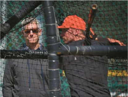  ?? KENNETH K. LAM/STAFF PHOTOS ?? Orioles executive vice president and general manager Mike Elias, left, watches batting practice during spring training at Ed Smith Stadium in Sarasota, Florida.