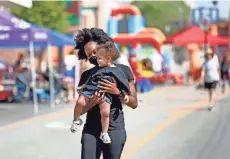  ??  ?? Alexandra Dyer, of the East Side, holds her 1-year-old daughter, Isla Gregory, as they explore the Avenue for All Festival.