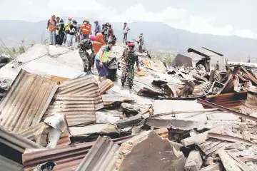  ?? — Reuters photo ?? Soldiers carry a body recovered from the ruins of houses after an earthquake hit Balaroa sub-district in Palu.