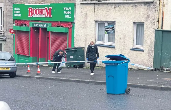  ??  ?? Police officers search the area near the scene of the incident on Cleghorn Street, Dundee, as an attempted murder probe was launched.