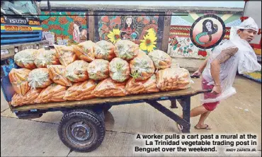  ?? ANDY ZAPATA JR. ?? A worker pulls a cart past a mural at the La Trinidad vegetable trading post in Benguet over the weekend.