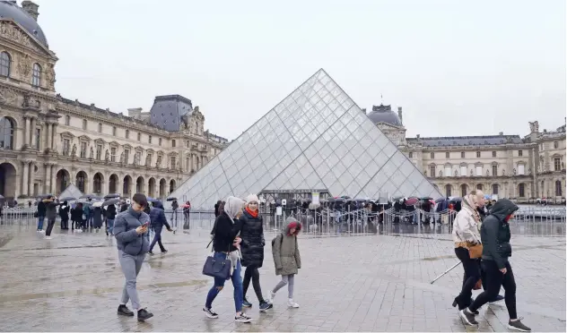  ?? Agence France-presse ?? ↑
People wait in front of the Louvre Pyramide in Paris on Sunday.