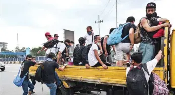  ?? — AFP ?? Residents get into a truck for a free ride home in Manila on Tuesday, as the government imposed measures to curb the spread of coronaviru­s, including suspending all public transport on the main Luzon island.