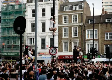  ?? Associated Press ?? ■ An England soccer fan climbs a lamppost as fans celebrate on the streets below in the London Bridge area of London after England won their quarterfin­al match against Sweden on Saturday at the 2018 World Cup.