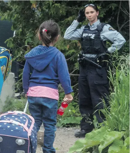  ?? TYLER ANDERSON / NATIONAL POST ?? An RCMP officer meets asylum seekers at the border crossing near Perry Mills, N.Y., in June.