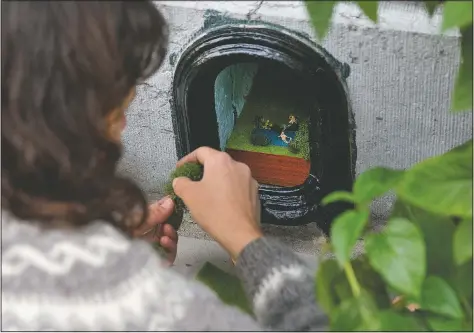  ?? (AP/Virginia Mayo) ?? Belgian artist Elke Lemmens installs a miniature scene of mermaids into a boot-scraper outside a front door in Antwerp, Belgium. Lemmens is transformi­ng disused boot-scrapers in the port city into miniature scenes depicting what is important in the lives of the owners of the house.
