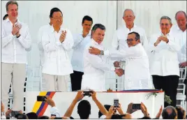  ?? FERNANDO VERGARA/ THE ASSOCIATED PRESS ?? Colombia’s President Juan Manuel Santos, front left, and the top commander of the Revolution­ary Armed Forces of Colombia Rodrigo Londono shake hands Monday in Cartagena, Colombia, after signing a peace agreement between Colombia’s government and the...
