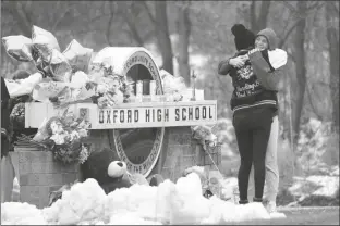  ?? PAUL SANCYA/AP ?? STUDENTS HUG AT A MEMORIAL at Oxford High School in Oxford, Mich., Wednesday. Authoritie­s say a 15-year-old sophomore opened fire at Oxford High School, killing four students and wounding seven other people on Tuesday.