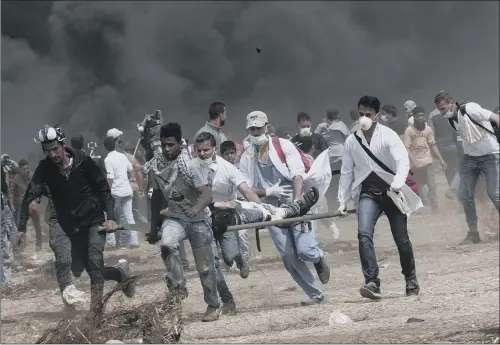  ??  ?? Palestinia­n medics evacuate a wounded youth during clashes with Israeli troops along Gaza’s border with Israel, east of Khan Younis, Gaza Strip yesterday.