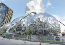  ?? Elaine Thompson, The Associated Press ?? Three large, glass-covered domeswere being built in April as part of the expansion of the Amazon.com campus in downtown Seattle. The company plans to build a second headquarte­rs in North America.