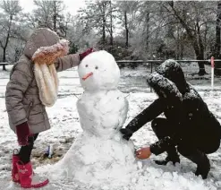  ??  ?? Camila Sustaita, 7, builds a snowman with her stepmother, Jay Denise Morales, in College Station. The sleet and snow fell just shy of Houston.