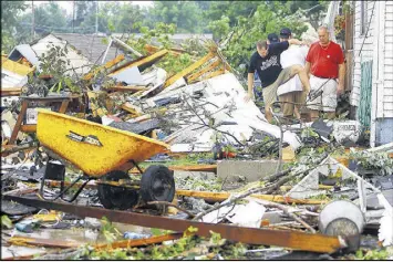  ?? TIM BATH / THE KOKOMO TRIBUNE ?? Brian Karraker and Tony Jarrett make their way out of Jarrett’s aunt’s house after checking on her in Kokomo, Ind., on Wednesday.