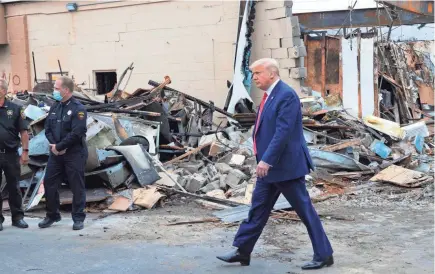  ?? MARK HOFFMAN/MILWAUKEE JOURNAL SENTINEL ?? President Donald Trump visits the burned remains of B & L Office Furniture on Tuesday in Kenosha. The president came to the city despite a plea from Wisconsin Gov. Tony Evers and other Democratic state leaders to stay away until the city has healed from unrest last week.