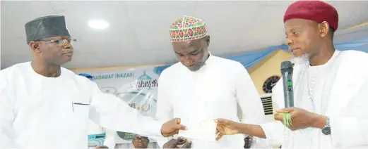  ??  ?? NASFAT Chief Missioner, Sheikh Maruf Abdulazeez Onike (right) presenting a cheque Jimoh Jubril (middle) with support of NAZAS Director, Dr. Daud Oniyide at the disburseme­nt ceremony in Lagos