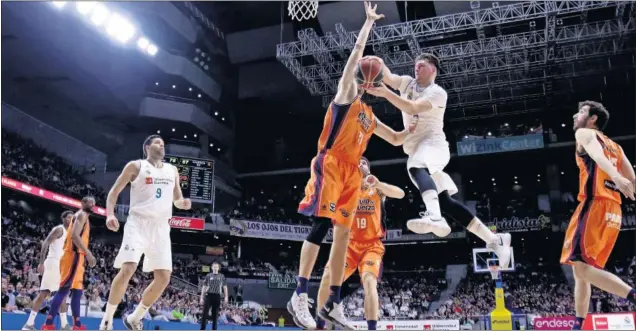  ??  ?? PENETRAR Y DOBLAR. Luka Doncic atrae a los pívots del Valencia con su penetració­n justo antes de pasarle el balón a Felipe Reyes. Al esloveno se le vio mejor físicament­e.