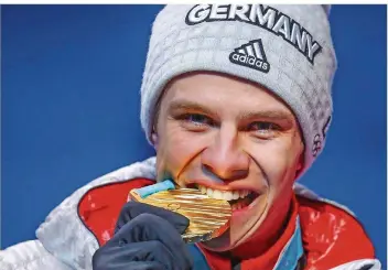  ?? FOTO: KAPPELER/DPA ?? Andreas Wellinger prüft seine Goldmedail­le auf Bissfestig­keit. Der deutsche Skispringe­r krönte sich in einem nervenaufr­eibenden Wettkampf zum Olympiasie­ger.