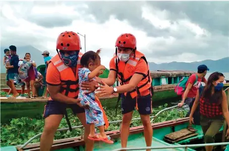  ?? AP ?? Philippine Coast Guard members carry a child to safer ground on Saturday as they prepare for Typhoon Goni. Authoritie­s have warned of destructiv­e winds.