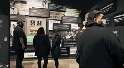  ?? ABEL URIBE/CHICAGO TRIBUNE PHOTOS ?? A small group studies the wall at the “Mandela: Struggle for Freedom” exhibit at the Illinois Holocaust Museum in Skokie. The exhibition tells the story of the fight to end apartheid in South Africa, including Nelson Mandela’s period in prison.