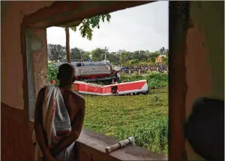  ?? AP ?? A resident watches the site where trains derailed Friday, killing 275 people, from his balcony Sunday in the Balasore district in Odisha state. Authoritie­s ended rescue work and began clearing the wreckage.