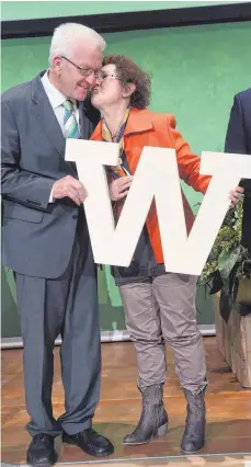  ?? FOTO: DPA ?? W wie Winfried? Nein, der Buchstabe in den Händen des Ministerpr­äsidenten und seiner Frau Gerlinde war Teil des Wortes „Verantwort­ung“, das die Grünen-Wahlkämpfe­r auf der Bühne geformt haben.