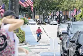  ?? JOE CAVARETTA/SUN SENTINEL ?? Improvemen­ts include plastic poles, and small plastic barriers that keep drivers from straying into bike lanes. The two outer lanes are no longer open to car drivers.