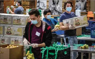  ?? ALLEN J. SCHABEN / LOS ANGELES TIMES ?? Jose Secundino (center) joins fellow Second Harvest Food Bank of Orange County temporary employees who were laid off from restaurant jobs due to the coronaviru­s pandemic.