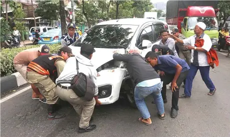  ?? GHOFUUR EKA/JAWA POS ?? TERPAKSA DIANGKAT: Mobil milik Pai dipindahka­n dengan tenaga manusia karena mobil derek tak kunjung datang, sementara kemacetan tak terelakkan.