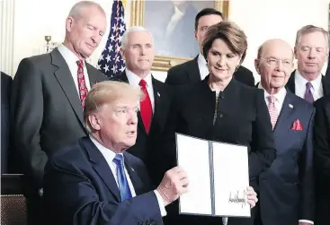  ?? MARK WILSON / GETTY IMAGES ?? U. S. President Donald Trump holds up a signed presidenti­al memorandum aimed at what he calls Chinese economic aggression at the White House on Thursday.